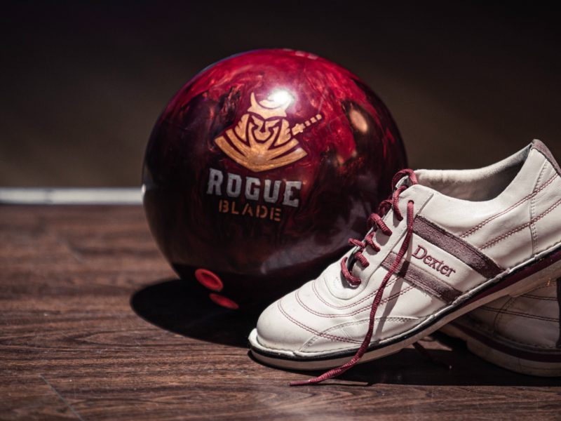A bowling shoe sits propped up in front of a bowling ball
